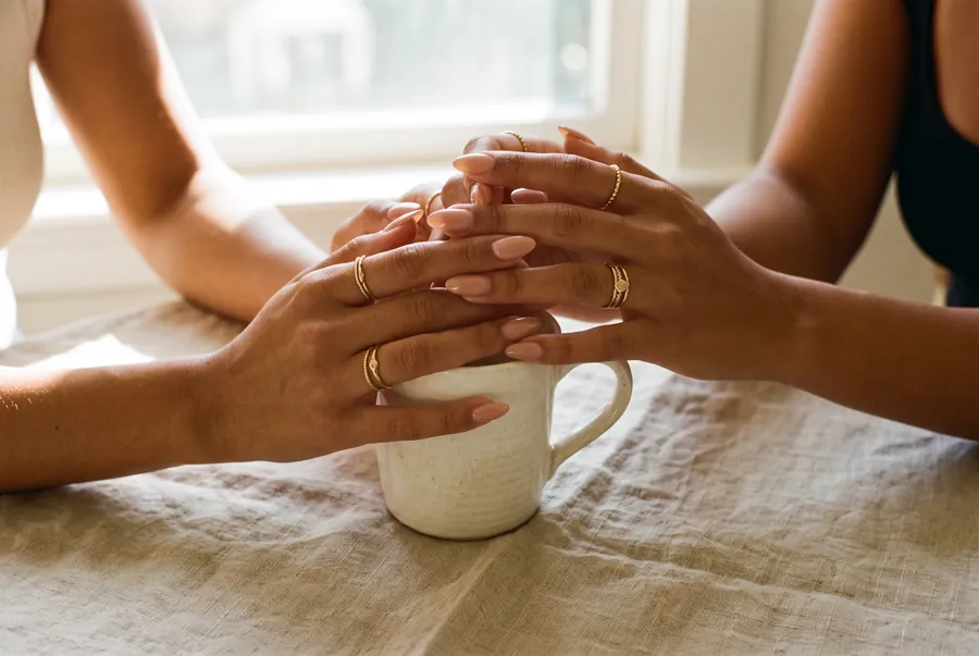 Dos manos con uñas nude sobre una taza